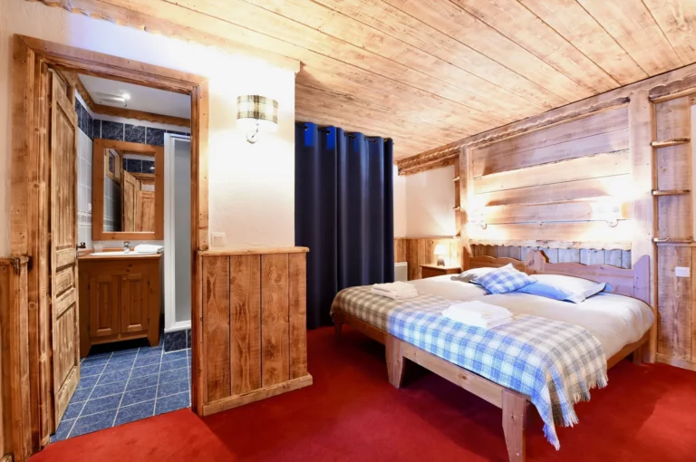 Chambre avec salle d'eau attenante et couvre-lit à carreaux dans l'appartement standard plain-pied 6 personnes des Ancolies
