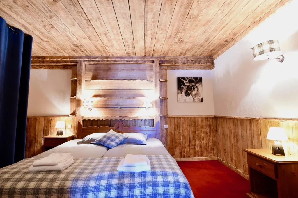 Chambre avec lit double, plaid écossais et tête de lit en bois dans l'appartement standard plain-pied 6 personnes des Ancolies