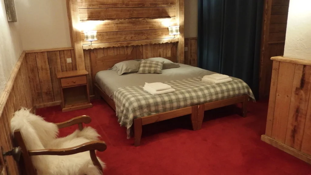 Chambre avec lit double, couvre-lit à carreaux et fauteuil peau de mouton dans l'appartement standard plain-pied 6 personnes des Ancolies