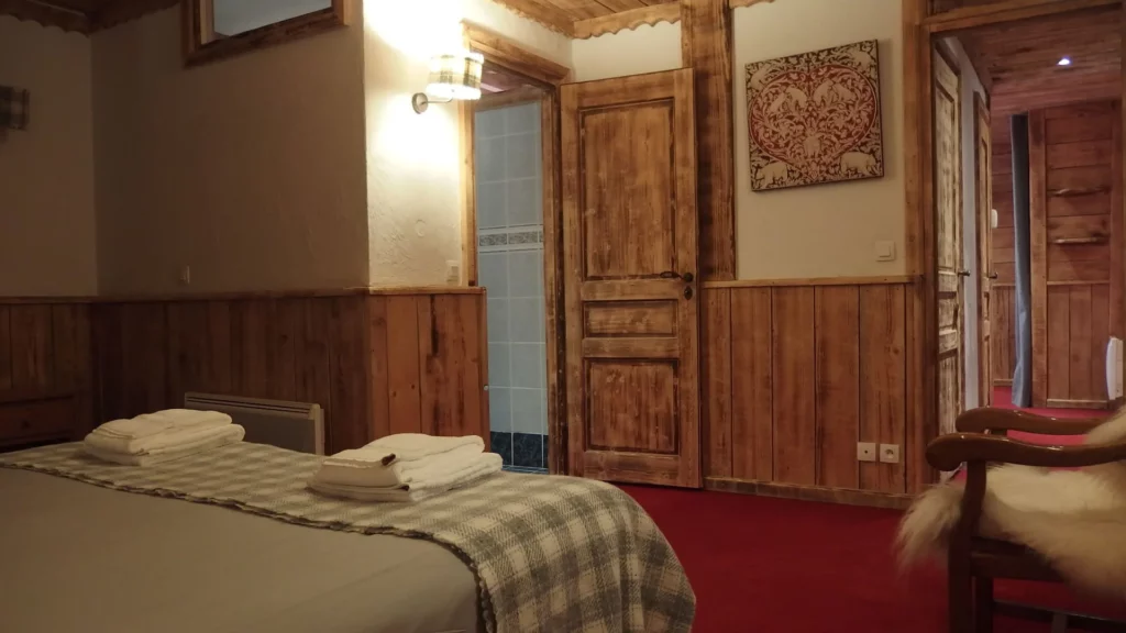 Chambre avec lits, tapisserie murale et fauteuil peau de mouton dans l'appartement standard plain-pied 6 personnes des Ancolies