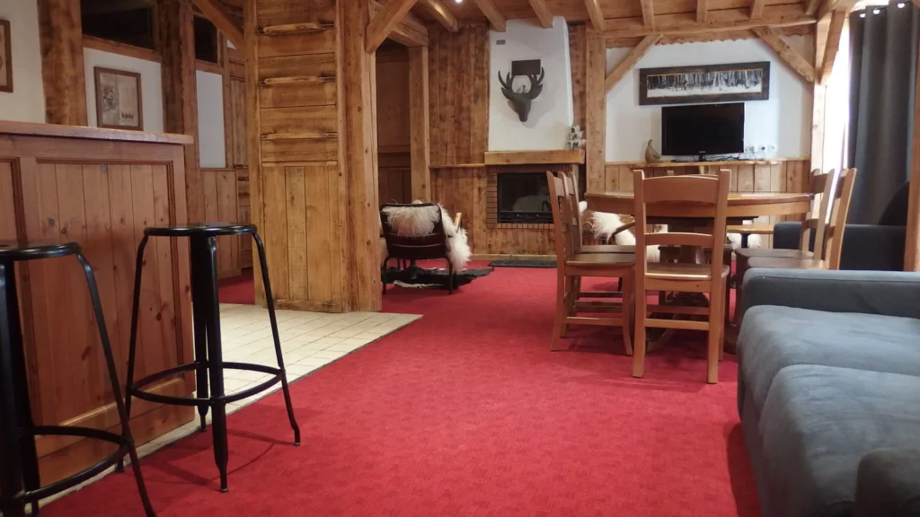 Vue du coin repas et salon avec tabourets hauts dans l'appartement standard plain-pied 6 personnes des Ancolies