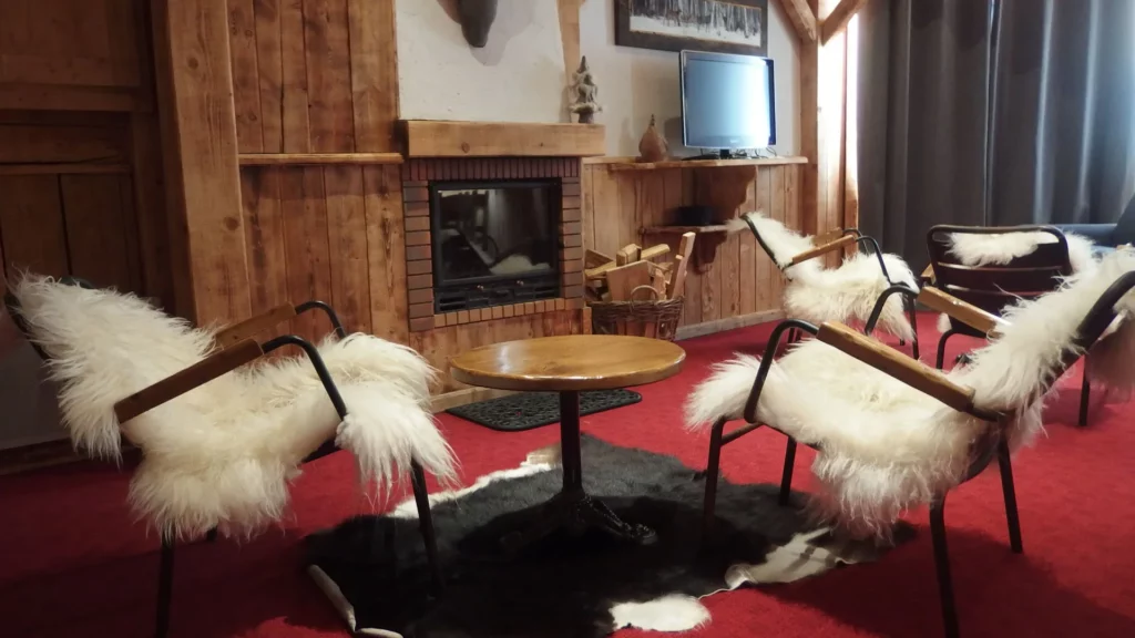 Coin cheminée avec fauteuils en peau de mouton dans l'appartement standard plain-pied 6 personnes des Ancolies