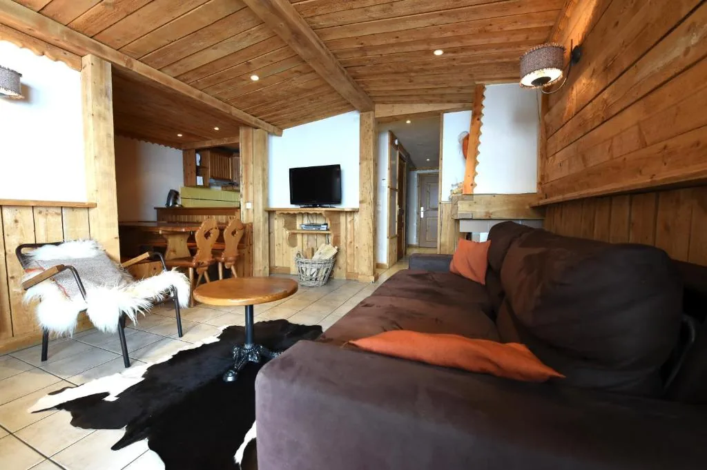 Salon avec canapé et coussins orangés dans l'appartement 8 personnes standard des Ancolies