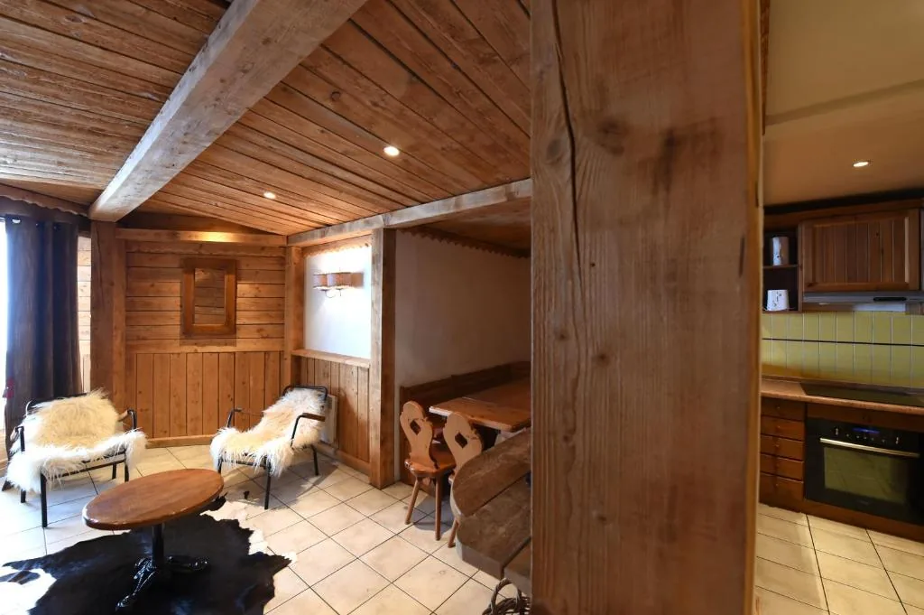 Coin salon avec fauteuils en peau de mouton et cuisine en fond dans l'appartement 8 personnes standard des Ancolies