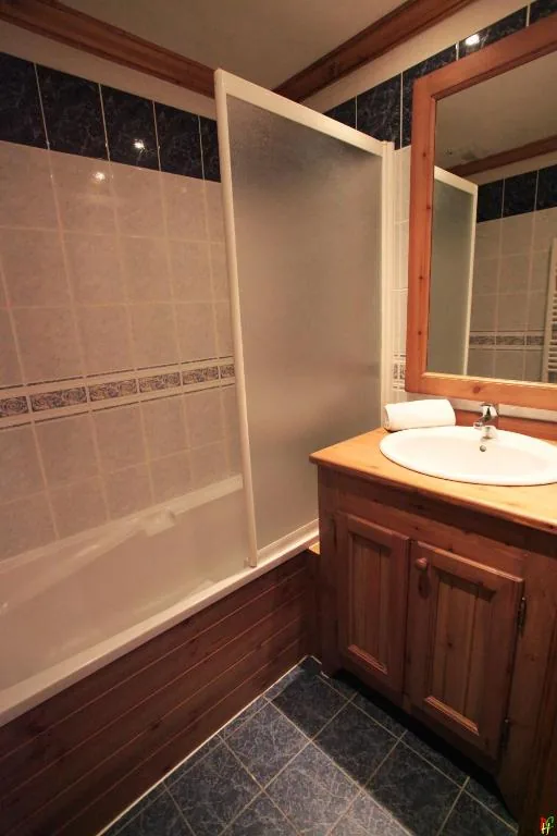 Salle de bain avec douche et carrelage bleu marine dans l'appartement 8 personnes standard des Ancolies