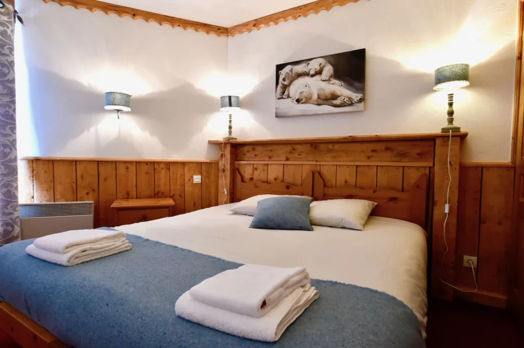 Deuxième chambre avec lit double et tête de lit en bois dans le duplex 6 personnes des Ancolies