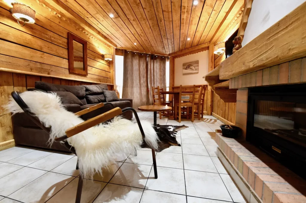 Coin salon avec cheminée et fauteuil peau de mouton dans le duplex 6 personnes de la résidence Les Ancolies